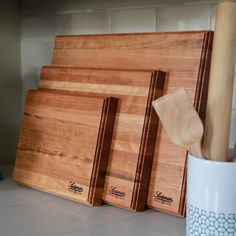 three chopping boards sitting on top of a counter next to a mug and knife