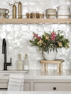 a vase with flowers sitting on top of a kitchen counter