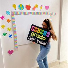 a woman holding a sign in front of a whiteboard that says quinto grad