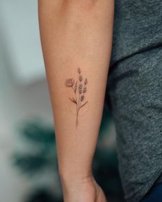 a woman's arm with a small flower tattoo on the left side of her arm