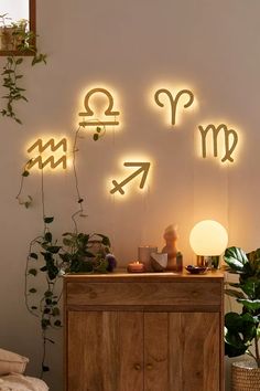 the zodiac signs are lit up on the wall next to a cabinet with plants in it