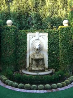 an outdoor fountain surrounded by hedges and plants