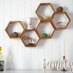 three hexagonal shelves on the wall with wine glasses and candles