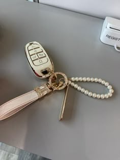 a cell phone with a key chain attached to it sitting on a table next to a remote control