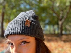 Give the gift of warmth and style! This knit beanie is perfect for hiking, camping, and perfect for keeping warm! Beanie is a dark charcoal gray color, and is made of a soft wool/acrylic blend. Attached is an engraved leather label tag with a brass rivet. The leather label is engraved on both sides, so whether you wear the hat with the brim up or down, the label will still show the design in the correct orientation. Choice of circle logo or trees available at checkout. Care - Hand wash, dry flat Gray One Size Fits Most Beanie Hat, Gray Beanie Cap, Gray Winter Hats For Outdoor, Gray Winter Outdoor Hats, Outdoor Beanie Cap, One Size Fits Most, Lightweight Adjustable Winter Beanie, Outdoor Soft Knit Beanie Cap, Lightweight Gray Hat For Outdoor Activities, Warm Gray Hats For Outdoor