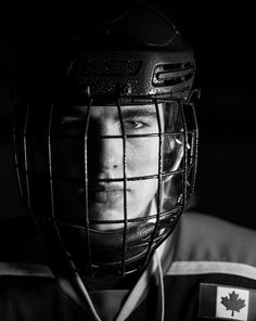 a black and white photo of a man wearing a hockey helmet with the canadian flag on it