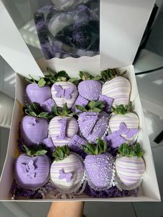 a box filled with purple and white chocolate covered strawberries