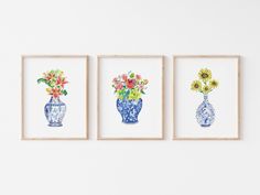 three vases with flowers are hanging on the wall