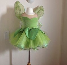 a green fairy dress on a mannequin stand in front of a white wall