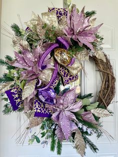 a wreath with purple and gold decorations hanging on a door