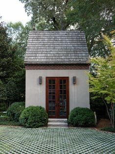 a small white house surrounded by trees and shrubbery with a door leading to it