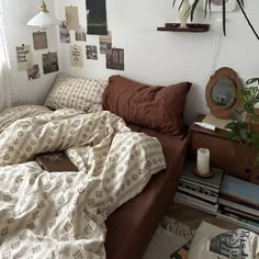 an unmade bed in a small room with lots of pictures on the wall above it