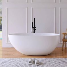 a large white bathtub sitting on top of a wooden floor next to a chair