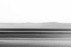 a black and white photo of an ocean with mountains in the background