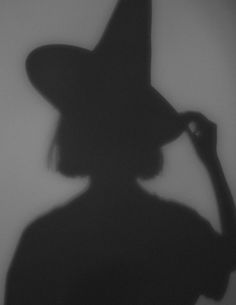 the shadow of a woman wearing a witches hat