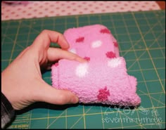 a person is holding a small pink object on a cutting board with a green surface