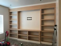 empty bookshelves in the corner of a room with tools and other items on the floor