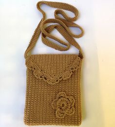 a brown crocheted purse with a flower on the front and an attached strap