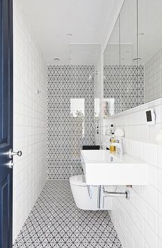 a white bathroom with black and white tiles on the floor, sink and mirror above it