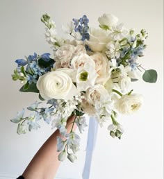 a bouquet of white and blue flowers in someone's hand