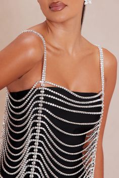 a woman wearing a black and white dress with pearls on it