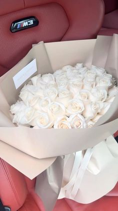 a bouquet of white roses sits in the back seat of a car