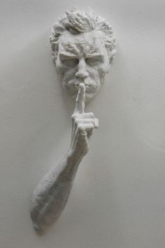 a white sculpture of a man holding a finger up to his mouth with both hands