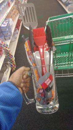 a person holding a plastic container filled with toothbrushes and other items in a store