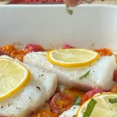 fish with lemons and tomatoes in a white dish