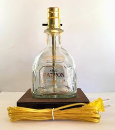 an old fashioned patron bottle sitting on top of a wooden stand next to some yellow cords