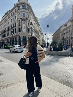 a woman standing on the sidewalk in front of a building