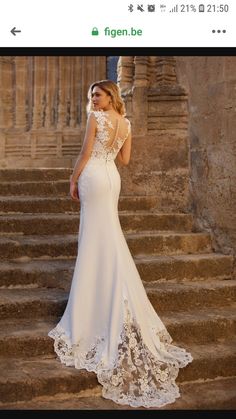 a woman in a white wedding dress standing on some steps with her back to the camera