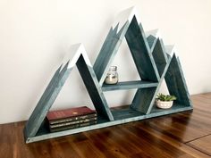 a wooden shelf with books on top of it next to a vase and some plants