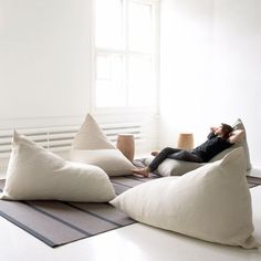 a person laying on a bean bag chair with three pillows in front of them and one sitting on the floor