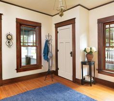 an empty room with three windows and a blue rug in front of the door,