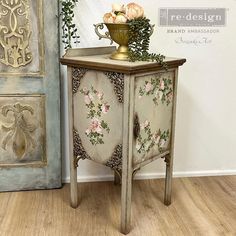 an antique cabinet with flowers painted on it and a vase filled with roses sitting on top