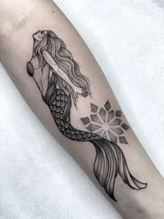 a woman's arm with a black and white tattoo design on the left forearm