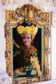 a woman dressed in traditional thai garb with flowers on her head is posing for the camera