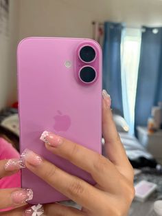 a woman holding an iphone in her hand with pink and white designs on the case