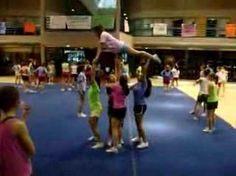 a group of people standing on top of a blue floor in a gym with one person doing a handstand