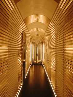 a long hallway with wooden slats on the walls and lights at the end that are lit up