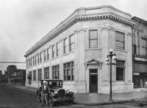 an old black and white photo of a building with cars parked in front of it