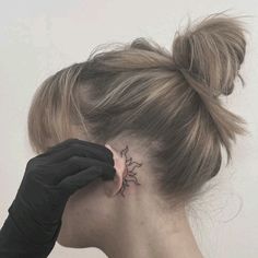 a woman with a tattoo on her neck and behind her ear is wearing black gloves