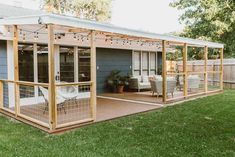 a screened in porch with patio furniture and string lights on the top deck, next to a blue house