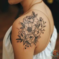 a woman's shoulder with flowers and leaves tattoo on her left arm, in black ink