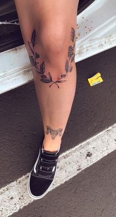 a woman's legs with tattoos on them and her shoes in front of a car