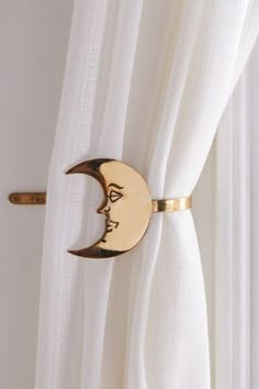 a curtain with a gold crescent moon on it's side hanging from a white curtain rod