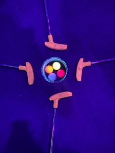 three different colored objects on purple surface with wooden sticks in the shape of four circles