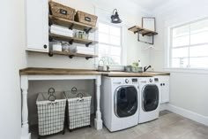 a washer and dryer in a white laundry room with open shelving on the wall