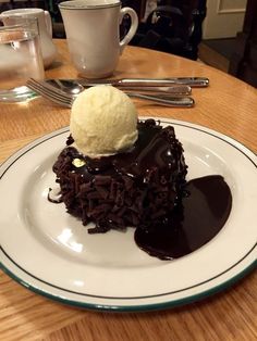 a piece of chocolate cake on a plate with ice cream in the middle and sauce drizzled over it